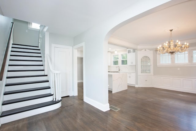 interior space with hardwood / wood-style floors, an inviting chandelier, and crown molding