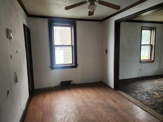 empty room with hardwood / wood-style floors, a textured ceiling, plenty of natural light, and ceiling fan