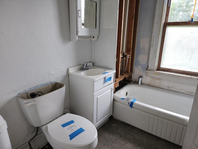 bathroom with a washtub, vanity, toilet, and a healthy amount of sunlight