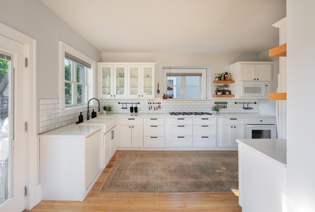 kitchen featuring white appliances, sink, white cabinetry, decorative backsplash, and light hardwood / wood-style flooring