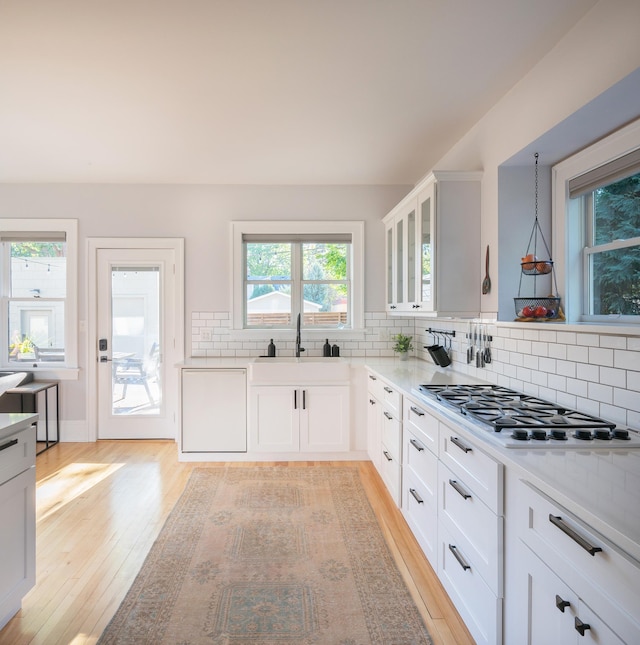 kitchen with stainless steel gas cooktop, white cabinets, decorative light fixtures, and light wood-type flooring