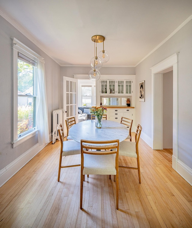 dining space featuring crown molding, radiator heating unit, and light wood-type flooring