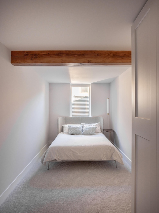 unfurnished bedroom featuring beamed ceiling and carpet flooring