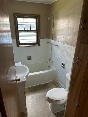 full bathroom with tile walls, vanity, tub / shower combination, and toilet