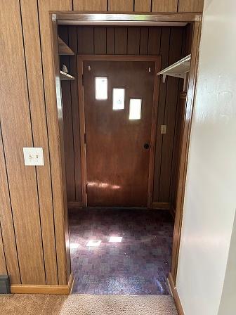 hall featuring wooden walls and dark colored carpet