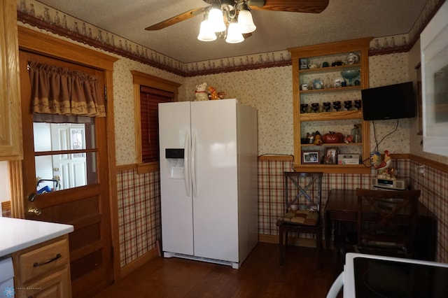 kitchen with a wainscoted wall, white fridge with ice dispenser, light countertops, and wallpapered walls