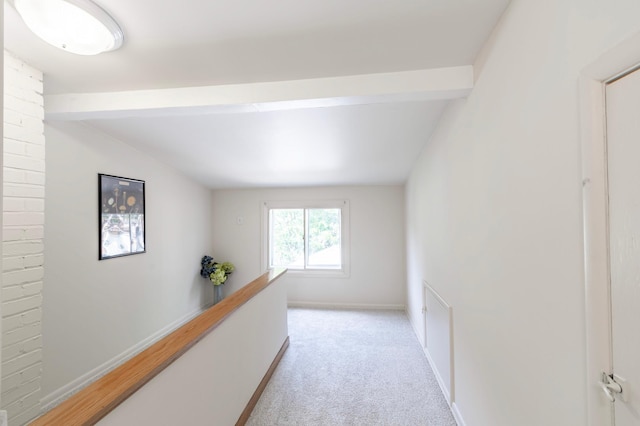 hall featuring beam ceiling, brick wall, and light carpet