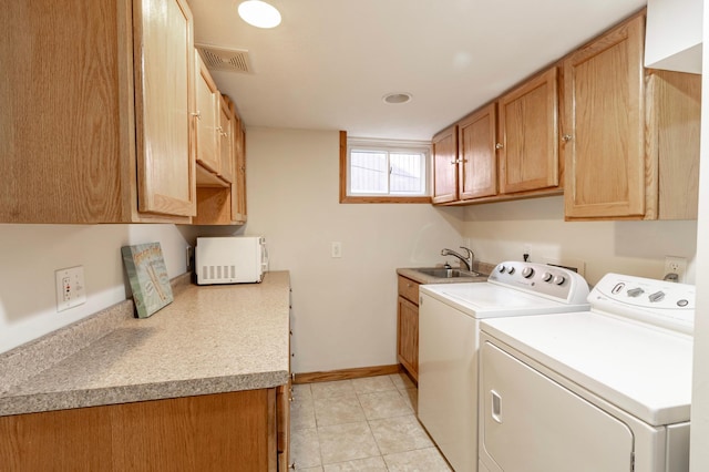 clothes washing area featuring light tile patterned floors, sink, independent washer and dryer, and cabinets