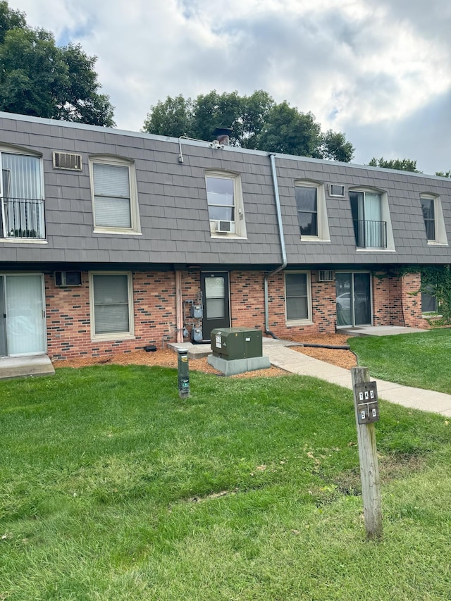 multi unit property featuring a front yard, mansard roof, and brick siding