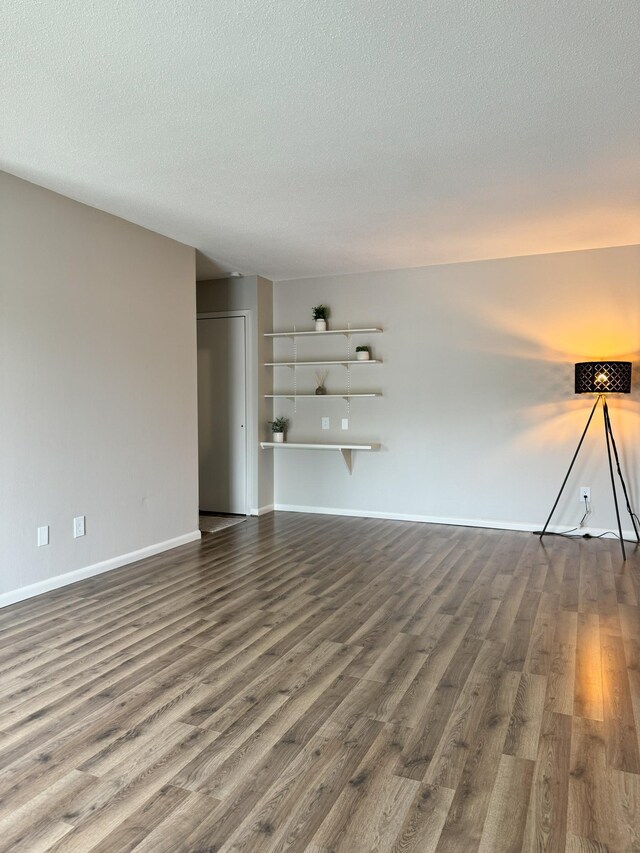 unfurnished living room with a textured ceiling and dark hardwood / wood-style flooring