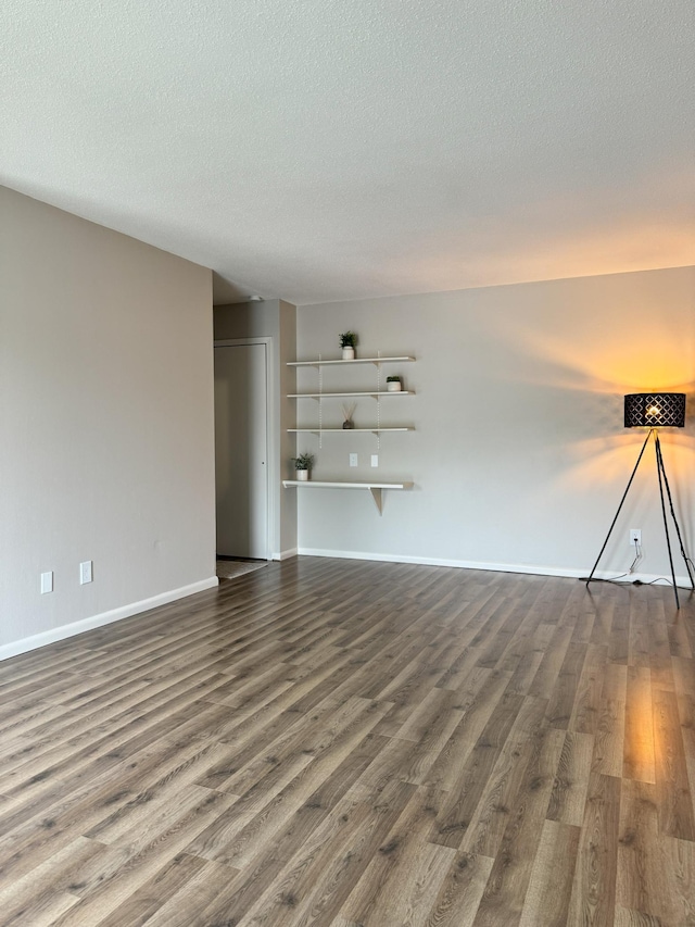 spare room with a textured ceiling, wood finished floors, and baseboards