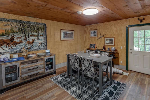 dining space with hardwood / wood-style floors, wood ceiling, and wooden walls