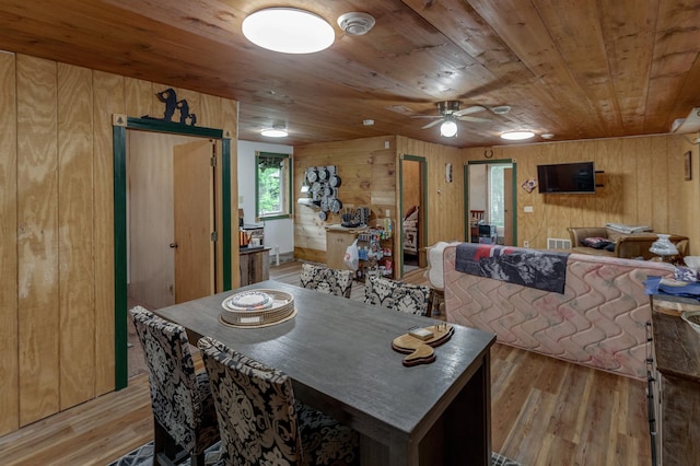 dining area featuring light wood-style floors, wood ceiling, visible vents, and wood walls