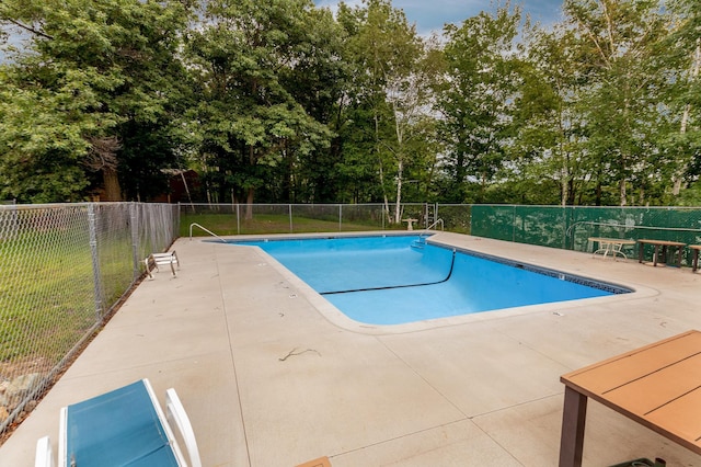 community pool with a patio area and fence