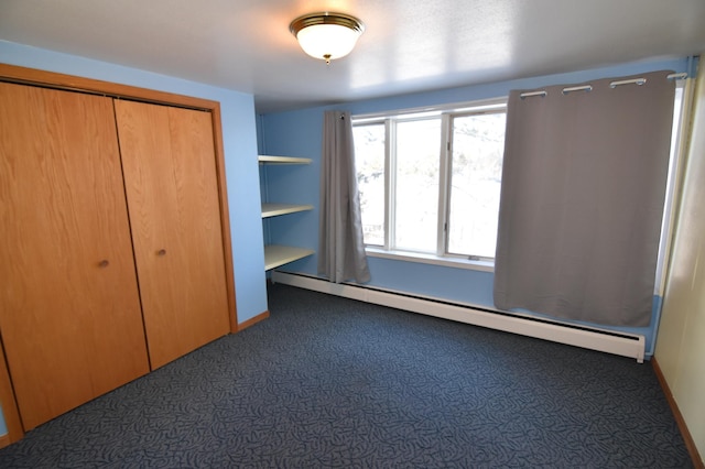 205 2nd Ave SE, Baudette, MN 56623 - unfurnished bedroom featuring a baseboard heating unit, dark colored carpet, and a closet