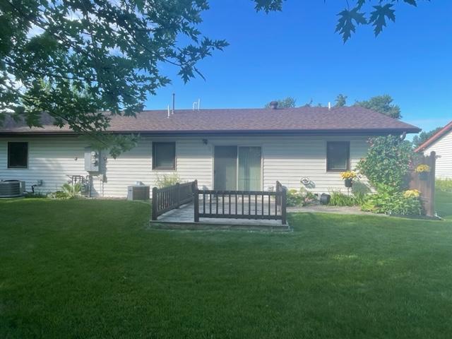 rear view of house featuring a lawn, cooling unit, and a deck