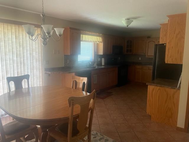 kitchen with pendant lighting, a chandelier, decorative backsplash, black appliances, and tile patterned floors