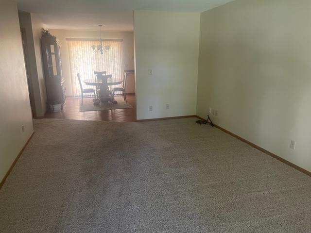 unfurnished room featuring an inviting chandelier and carpet flooring