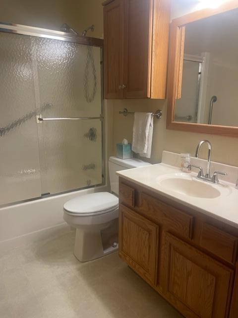 full bathroom with shower / bath combination with glass door, vanity, and toilet