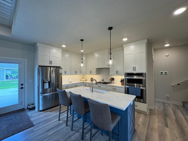 kitchen with stainless steel appliances, white cabinetry, sink, and dark hardwood / wood-style floors