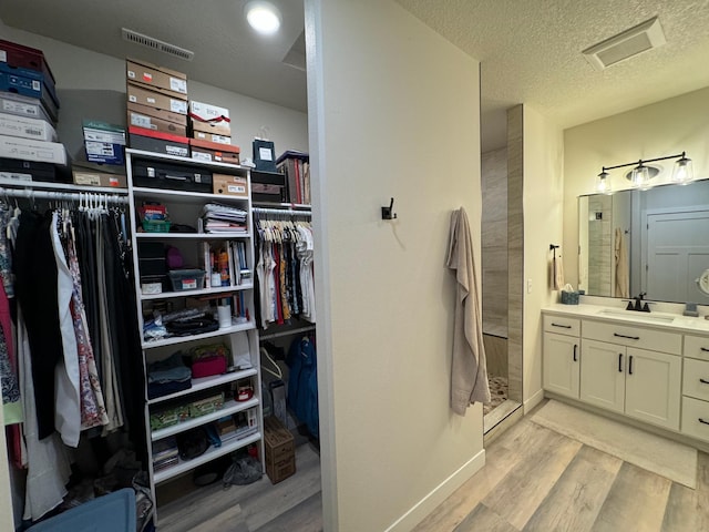 bathroom with vanity, hardwood / wood-style floors, a textured ceiling, and walk in shower