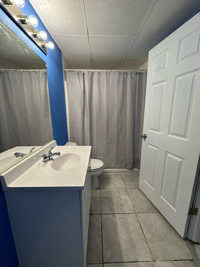 bathroom with a paneled ceiling, a shower with curtain, vanity, tile patterned floors, and toilet