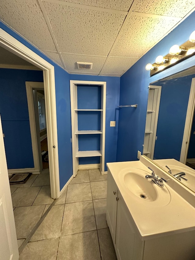 bathroom featuring vanity, tile patterned flooring, and a drop ceiling