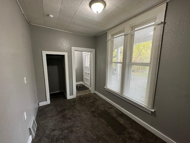 unfurnished bedroom featuring dark colored carpet and a closet