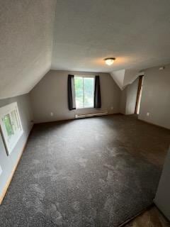 additional living space featuring vaulted ceiling and dark carpet