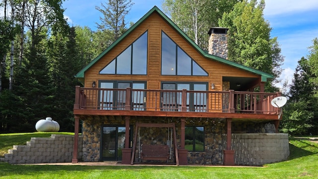 rear view of house with a deck, stone siding, a yard, and a chimney