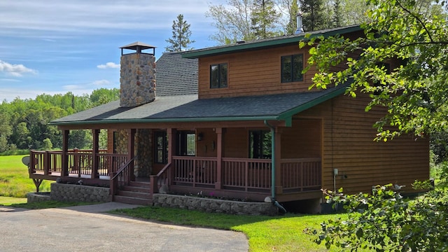 view of front of house with covered porch, roof with shingles, and a chimney