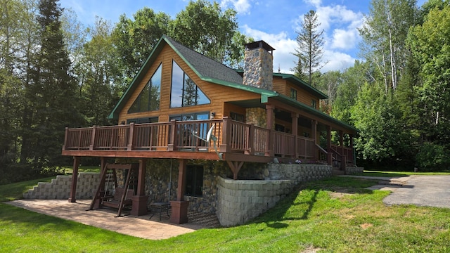 back of property with a wooden deck, a yard, and a patio area