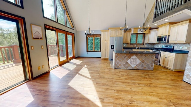 kitchen featuring an inviting chandelier, light wood-type flooring, hanging light fixtures, high vaulted ceiling, and appliances with stainless steel finishes