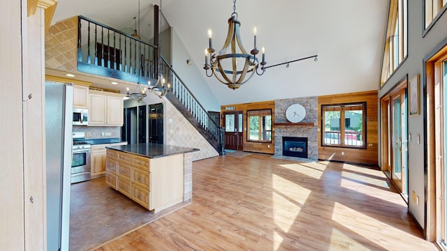 kitchen featuring a high ceiling, light hardwood / wood-style flooring, a stone fireplace, appliances with stainless steel finishes, and a center island