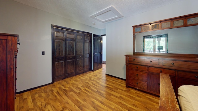 bedroom with a textured ceiling, a closet, and light hardwood / wood-style flooring