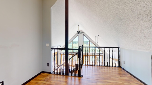 interior space featuring lofted ceiling, wood-type flooring, a textured ceiling, and ceiling fan