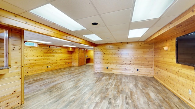 spare room featuring a paneled ceiling, wood walls, and wood-type flooring