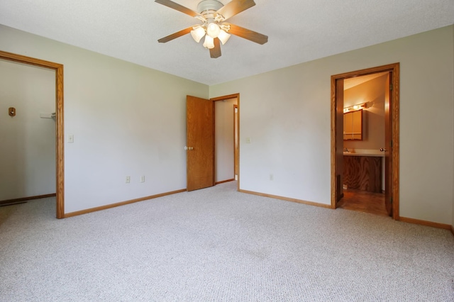 unfurnished bedroom with ceiling fan, ensuite bathroom, and carpet flooring