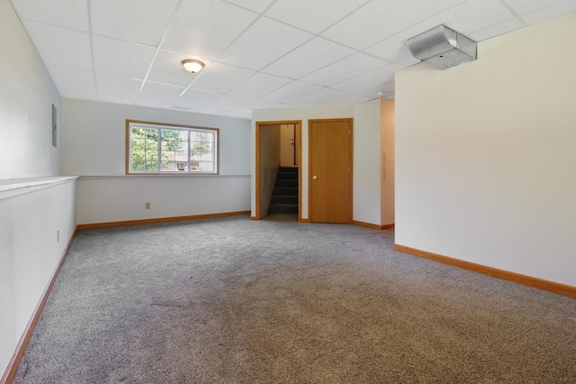 carpeted spare room with a drop ceiling