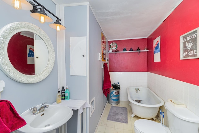 bathroom with tile walls, a bath, sink, and toilet