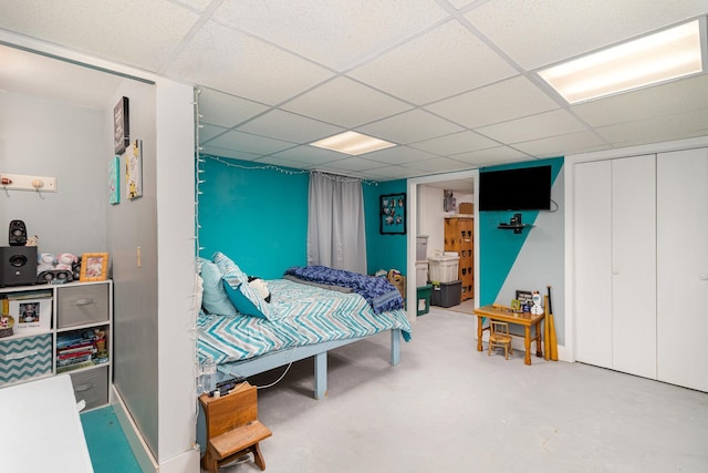 bedroom featuring concrete flooring, a closet, and a paneled ceiling