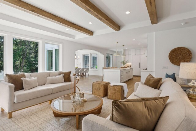 living room featuring beamed ceiling and light wood-type flooring