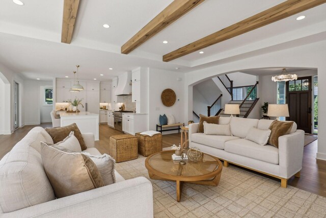 living room featuring a wealth of natural light, light hardwood / wood-style flooring, a chandelier, and beam ceiling