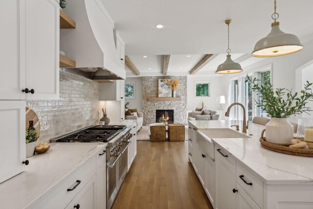 kitchen with a fireplace, beam ceiling, light hardwood / wood-style flooring, decorative backsplash, and white cabinetry