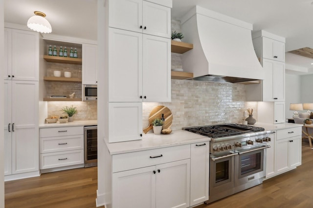 kitchen with custom exhaust hood, light wood-type flooring, backsplash, and appliances with stainless steel finishes