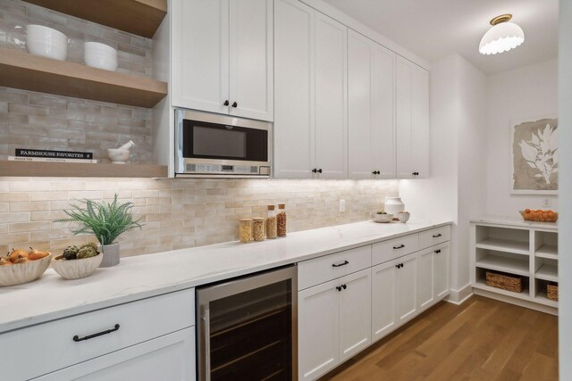 kitchen featuring backsplash, stainless steel microwave, wine cooler, light hardwood / wood-style flooring, and white cabinetry