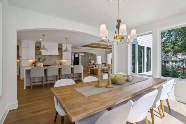 dining space with hardwood / wood-style flooring, beamed ceiling, and a chandelier