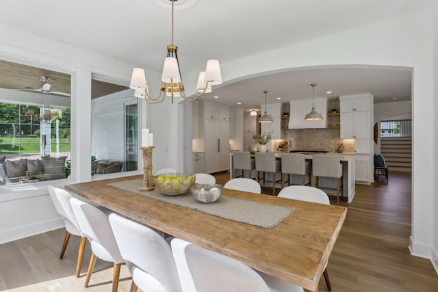 dining space with ceiling fan with notable chandelier and wood-type flooring