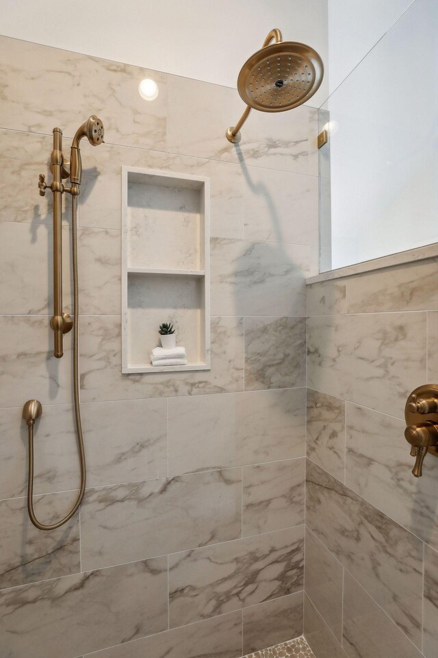 bathroom with tiled shower and built in shelves