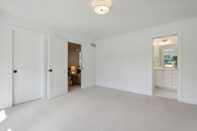 unfurnished bedroom with light colored carpet, ensuite bathroom, and sink